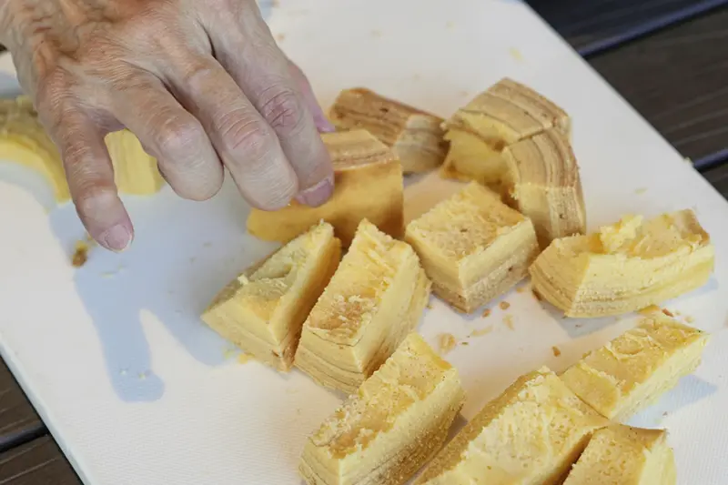Staff and participants try out baked Baumkuchen, a German layered cake, during a workshop of Juchheim Ninoshima Welcome Center and Outdoor Activity Camp Monday, July 7, 2025, at Ninoshima island in Hiroshima, western Japan. (AP Photo/Eugene Hoshiko)