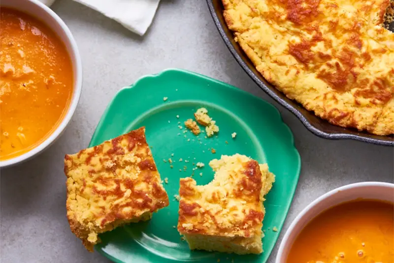 This image shows a recipe for cheddar cornbread baked in a cast iron skillet;. (Katie Workman via AP)