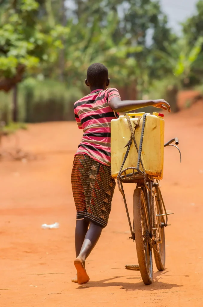 A Kid Walking on the Street while Pulling a Bicycle. Photo by PRINCE NIZEYIMANA
